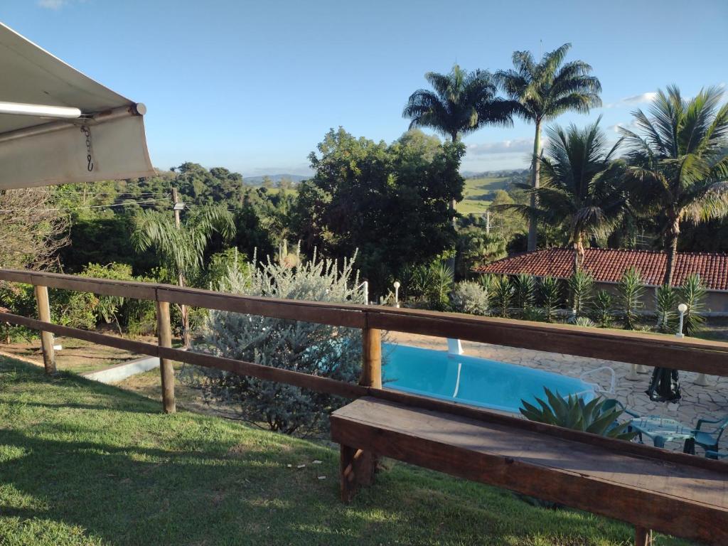 索科罗Chácara pedacinho do céu的坐在游泳池旁的草地上的木凳
