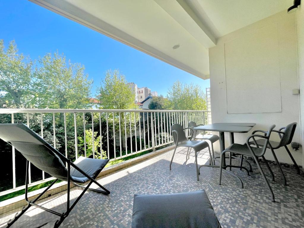 比亚里茨Splendide appartement de 75m2 avec place de parking à Biarritz tout inclus的阳台的天井配有桌椅