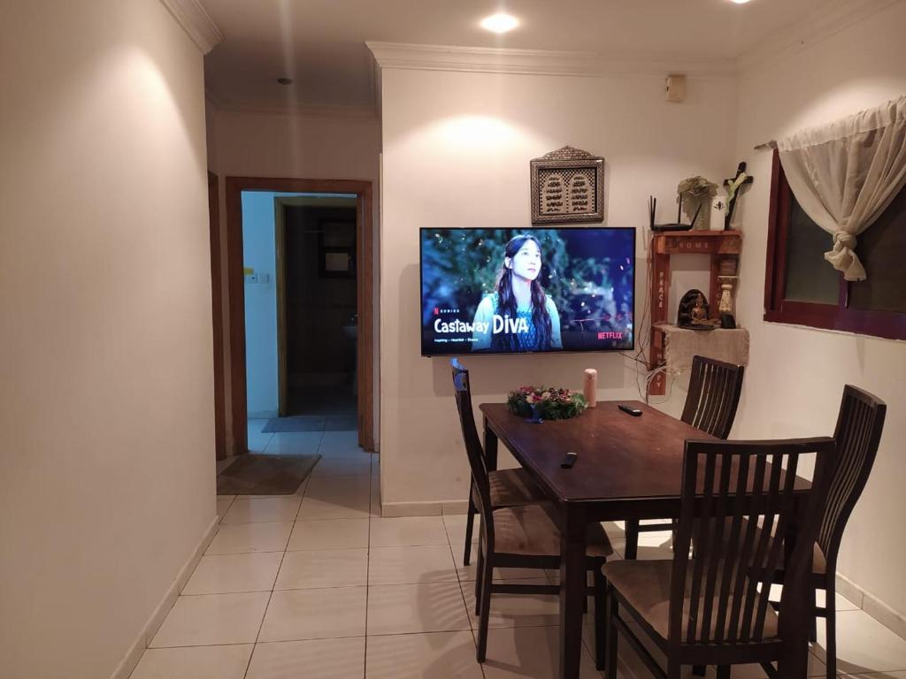 沙迦Family Room In Sharjah的一间设有桌子和墙上电视的用餐室