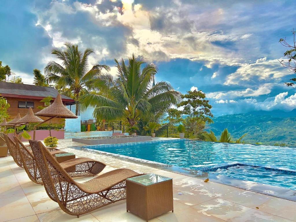 宿务Mabini Sky View Resort的一个带椅子和树木的游泳池以及山