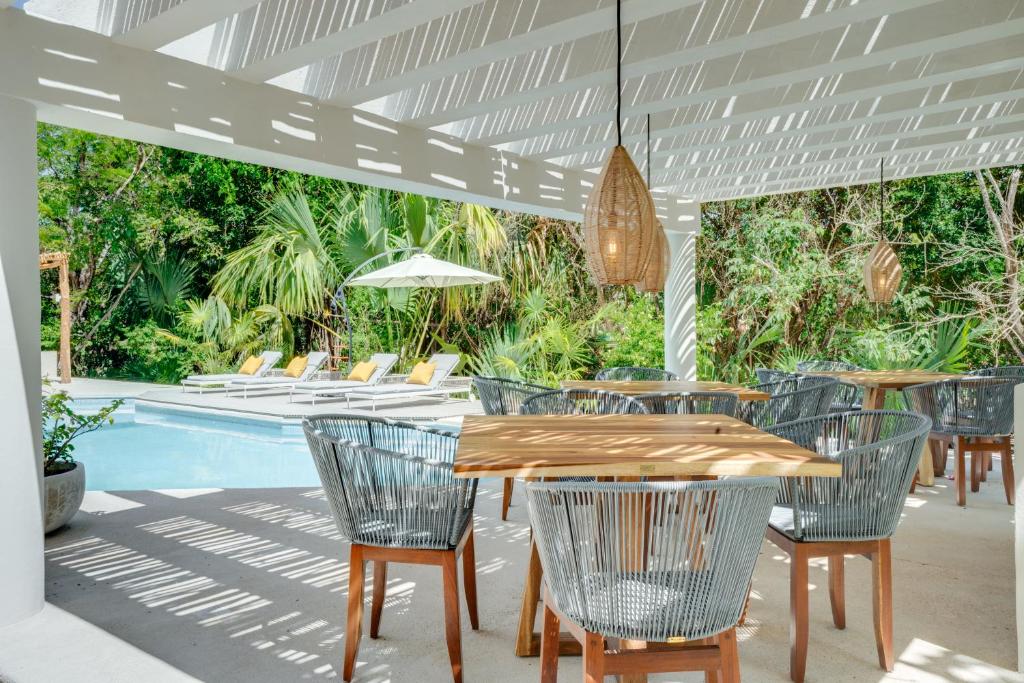 阿文图拉斯港Casa Manglar Riviera Maya的池畔露台配有桌椅
