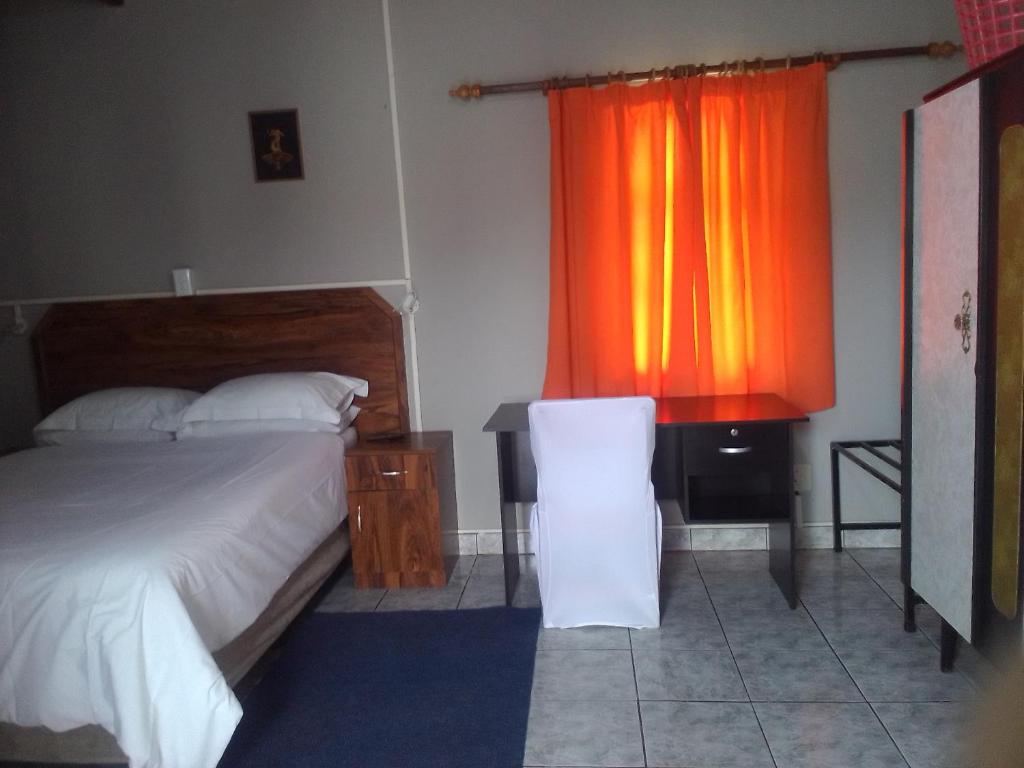 鲸湾港FEATHERS INN GUEST HOUSE的一间卧室配有床和橙色窗帘