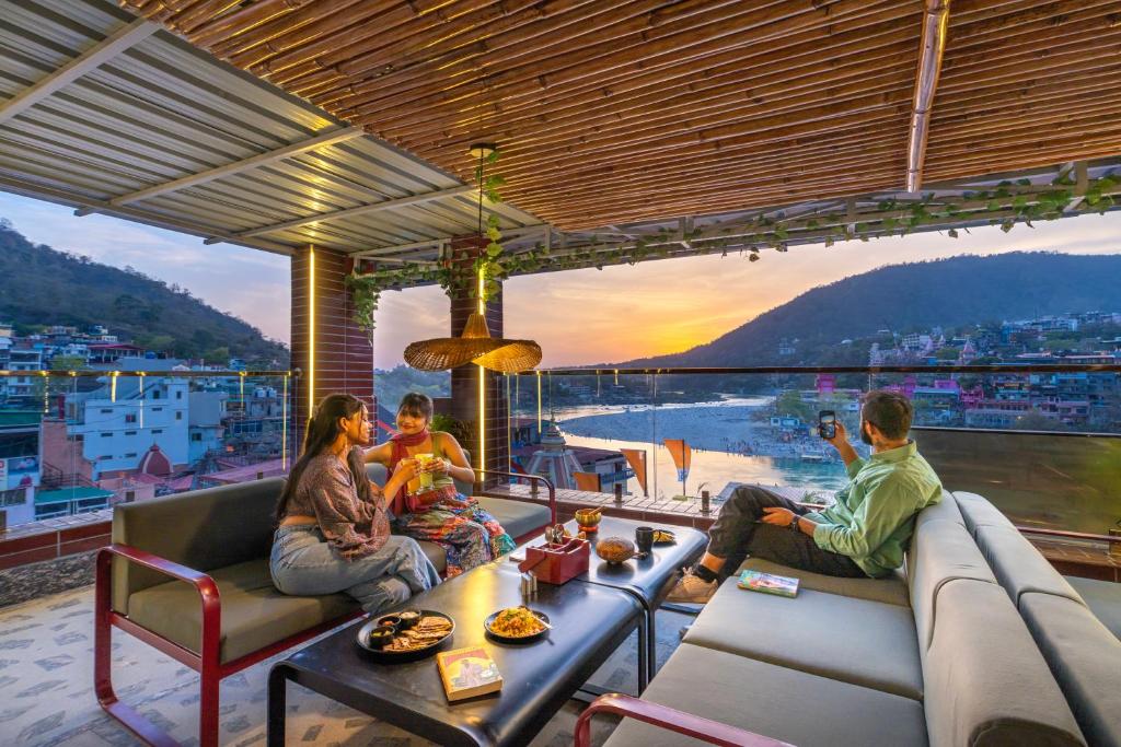 瑞诗凯诗The Hosteller Rishikesh, Ganges的一群人坐在阳台上欣赏日落