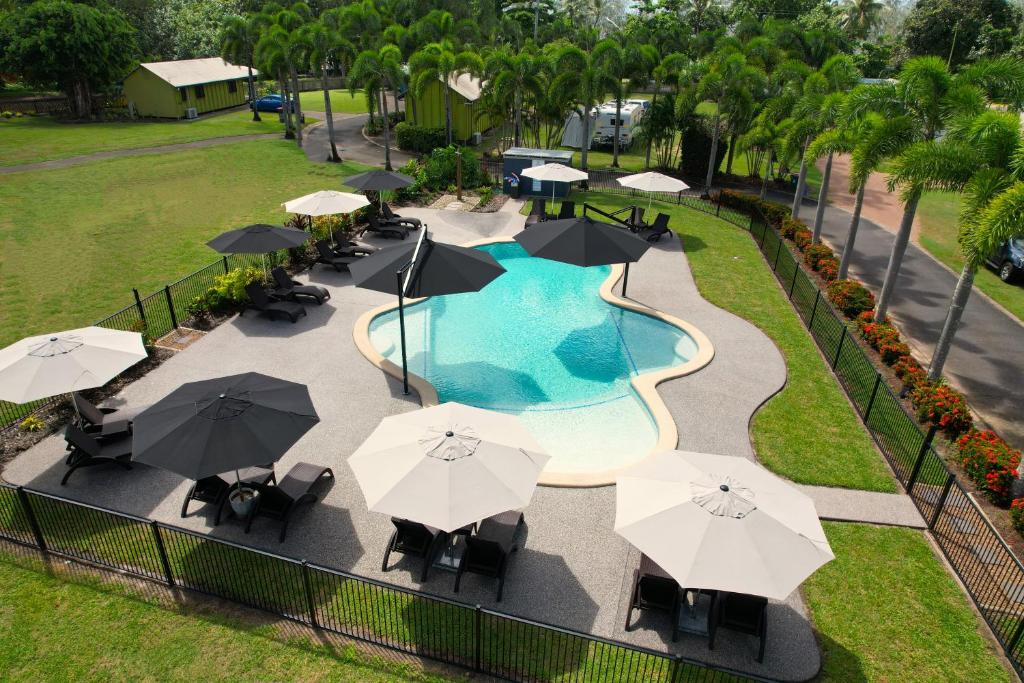 米申海滩Bali Hai Child Free Holiday Park Mission Beach的享有带遮阳伞和椅子的游泳池的顶部景致