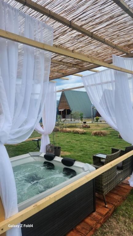 乌尔齐尼olive garden farm的后院的热水浴池配有白色窗帘