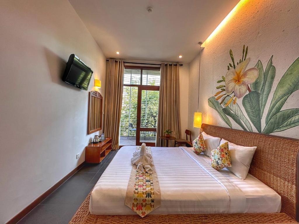 金边Monsoon Riverside Hotel的一间卧室配有一张带电视和花卉壁画的床。