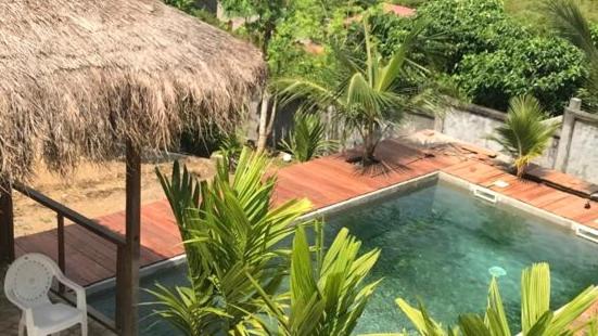 克里比Villa tropical avec vue sur l'océan atlantique的度假村内的游泳池,带椅子和小屋