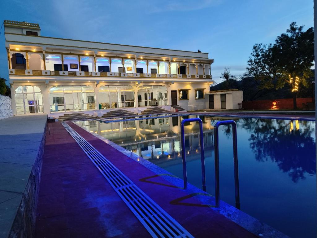 乌代浦Monkey Retreat Resort的一座大型建筑,前面设有一个游泳池
