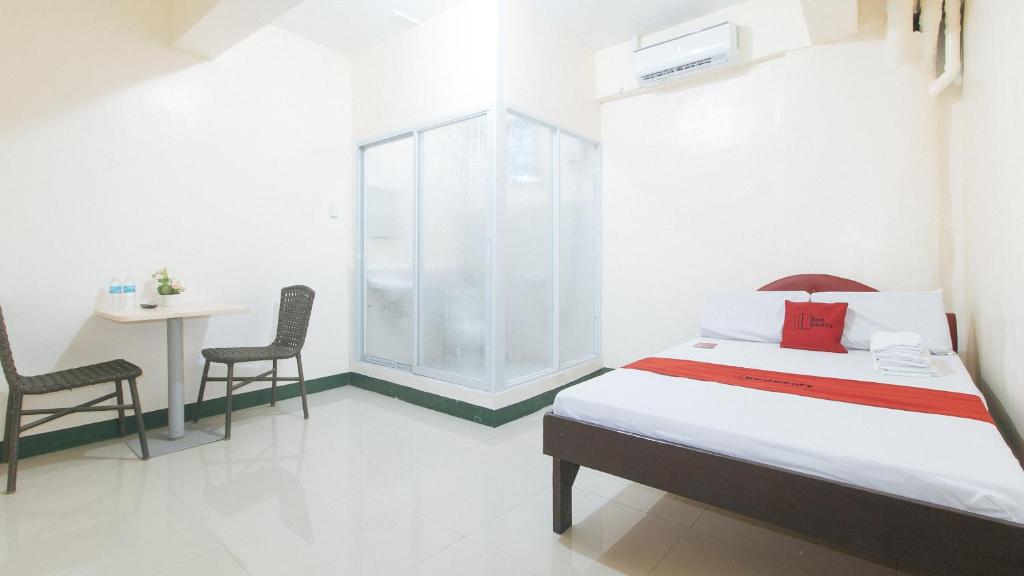 马尼拉RedDoorz @ Western Bicutan Transients Inn的卧室配有一张床和一张桌子及椅子