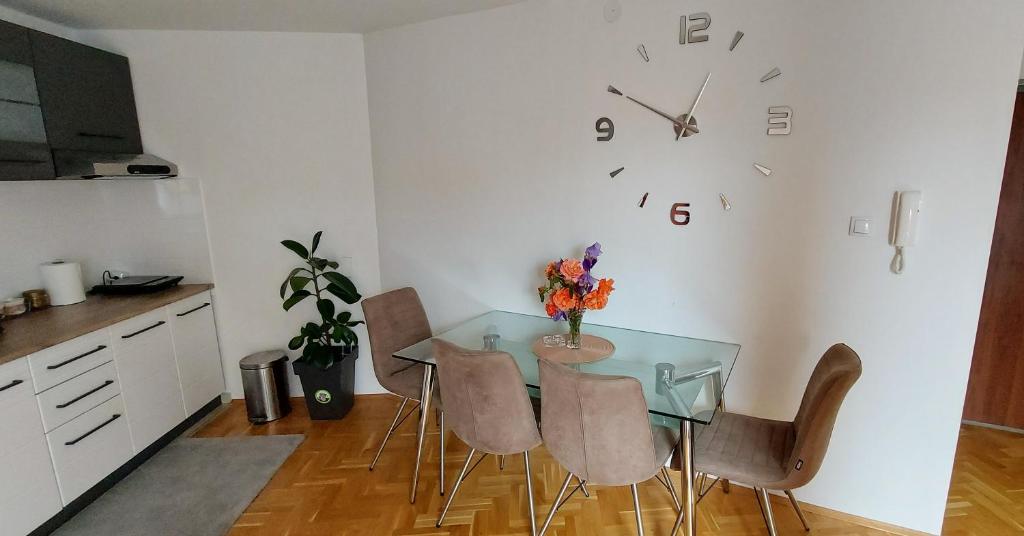 波扎雷瓦茨Apartman Panorama的餐桌、椅子和墙上的时钟