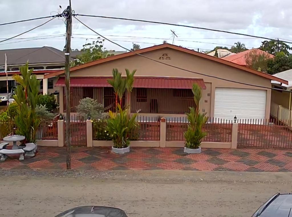 帕拉马里博Vakantiehuis Paramaribo的前面有栅栏和植物的房子