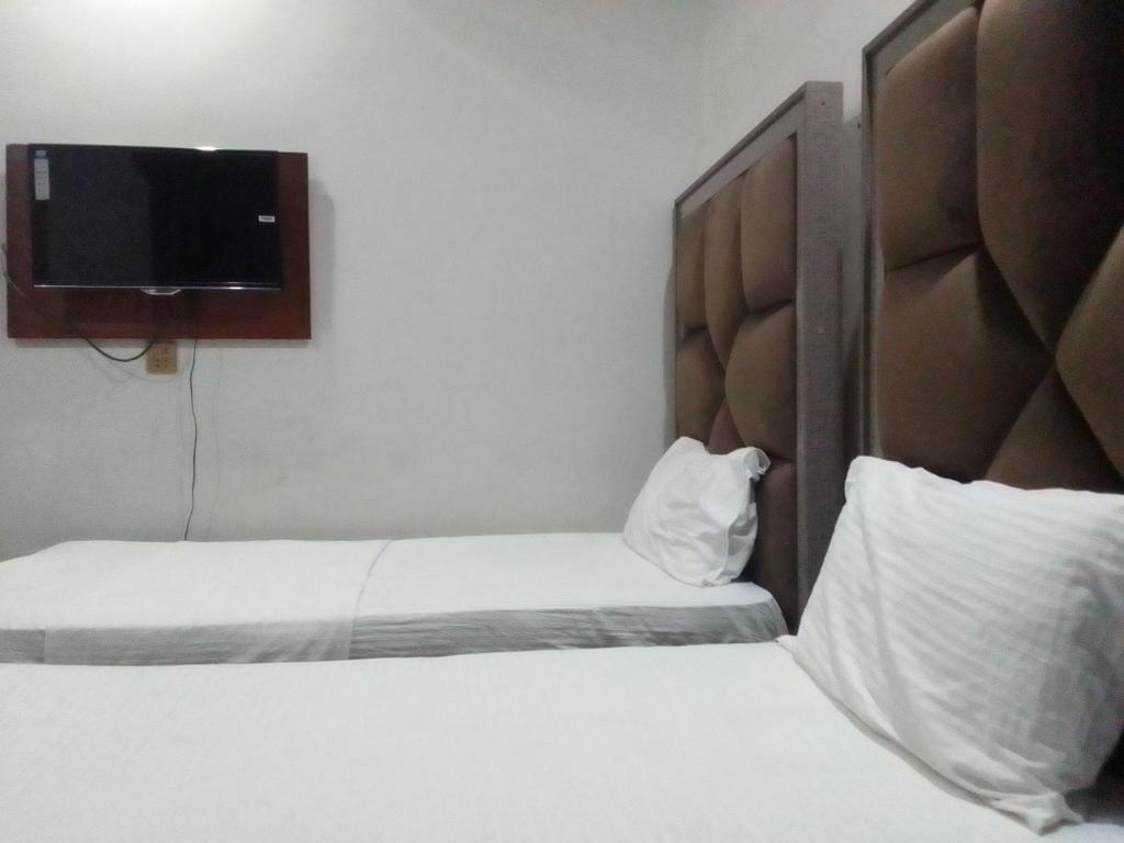 拉合尔Dove Inn Family Residency Johar Town的酒店客房设有两张床和一台平面电视。