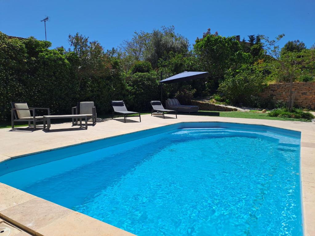 滨海圣西尔Chambre indépendante climatisée, terrasse 100M2 et salle d'eau的蓝色的游泳池配有椅子和桌子