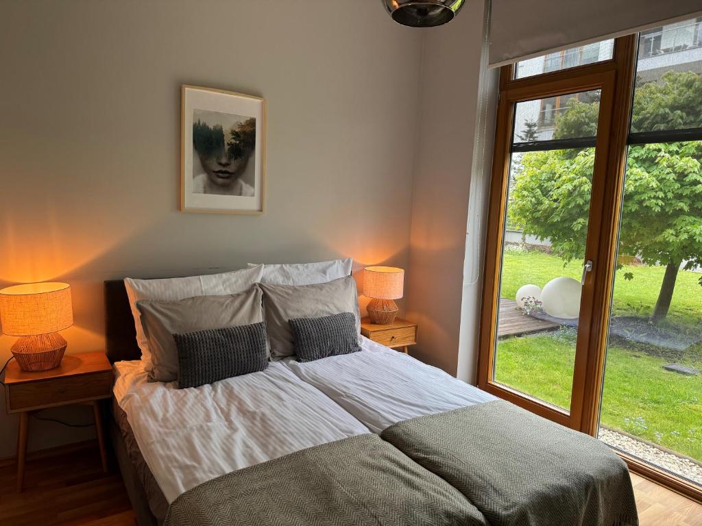 华沙WILANOWSKA apartment & garden的一间卧室配有一张带两盏灯的床和一扇窗户。
