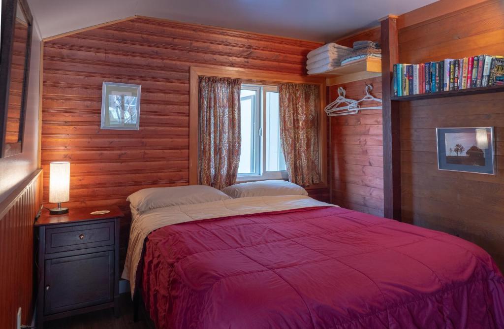 班夫山坡简易别墅的一间卧室设有红色的床和窗户。
