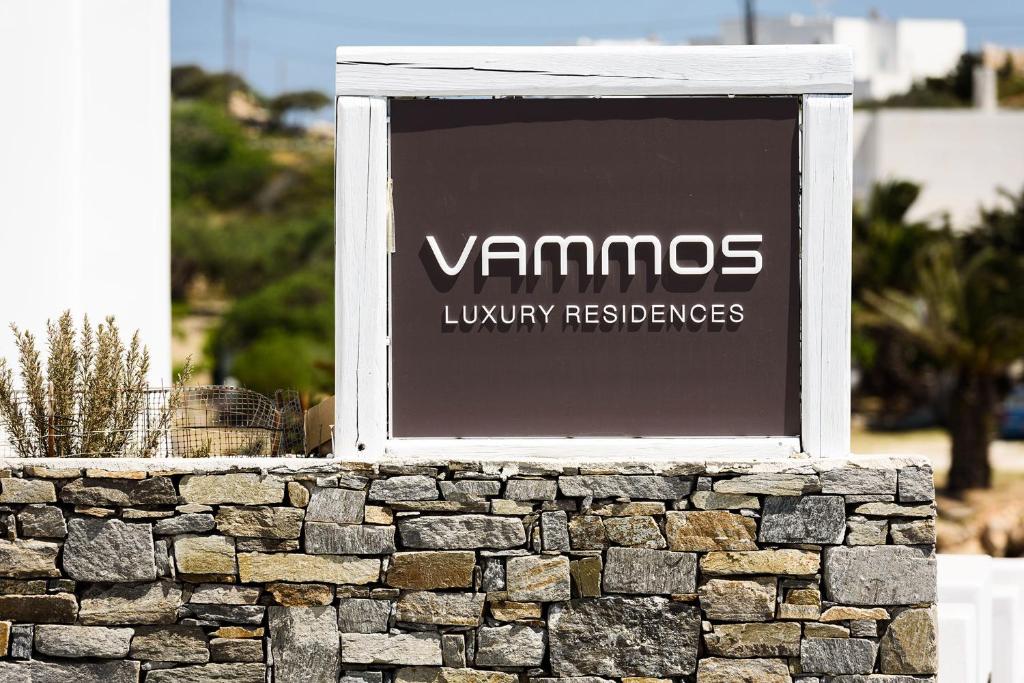 纳乌萨Vammos Luxury Apartments的石墙顶上的标志