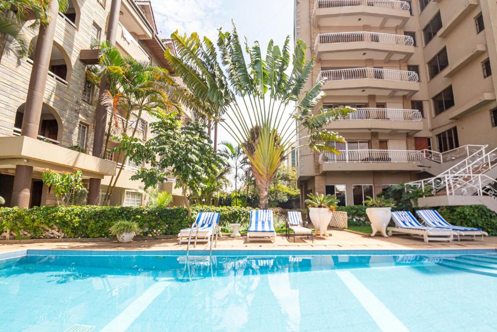 内罗毕Eldon Suites & Apartments的一座带椅子和棕榈树的建筑前的游泳池