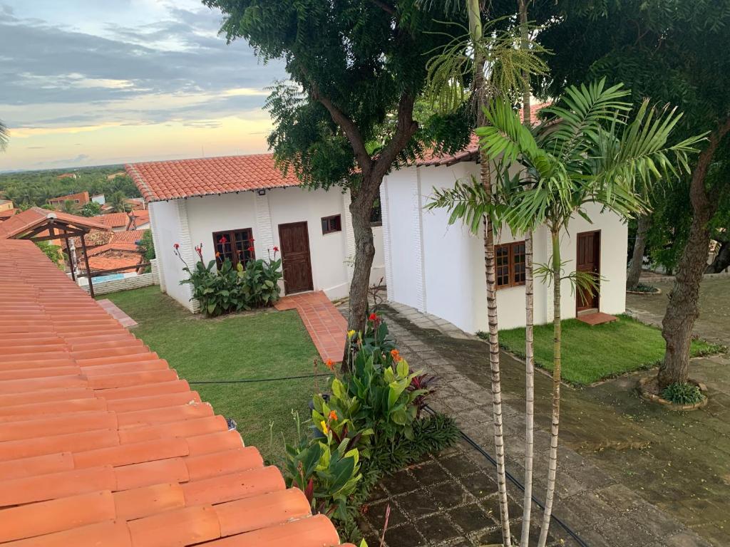 贝贝里比Morro Branco Suítes - Hospedaria Morro Branco的前面有一棵树的白色房子