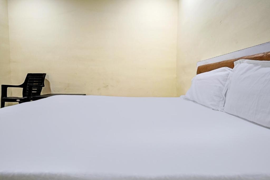 孟买OYO Sai Villa Lodging & Bording的一张带白色枕头的床和一把椅子