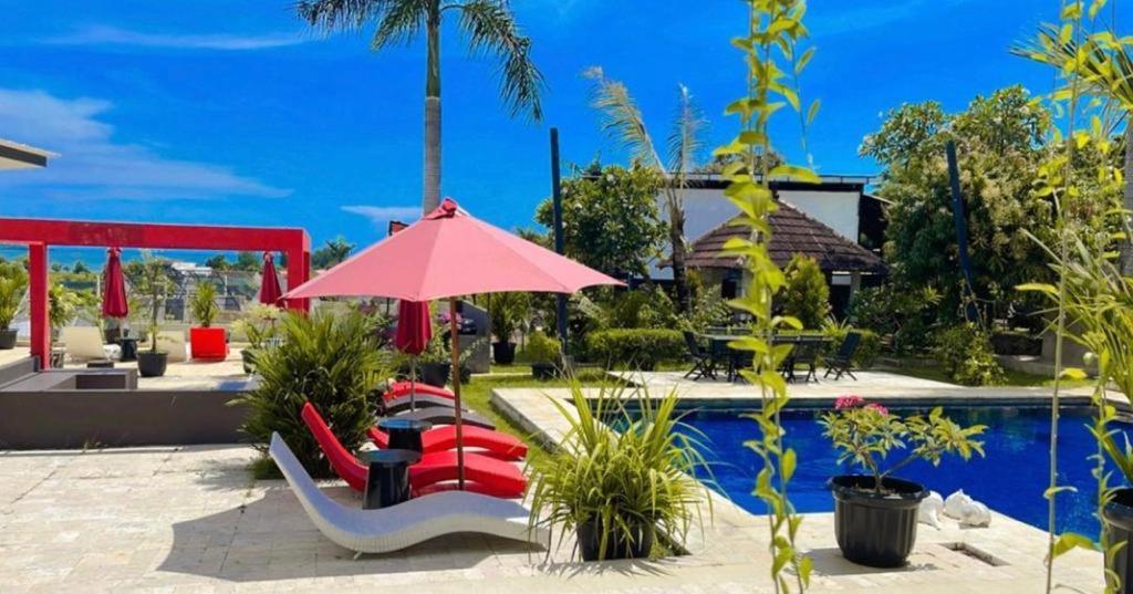 哲帕拉Lucca Resort & Residence的一个带红色遮阳伞和椅子及桌子的游泳池