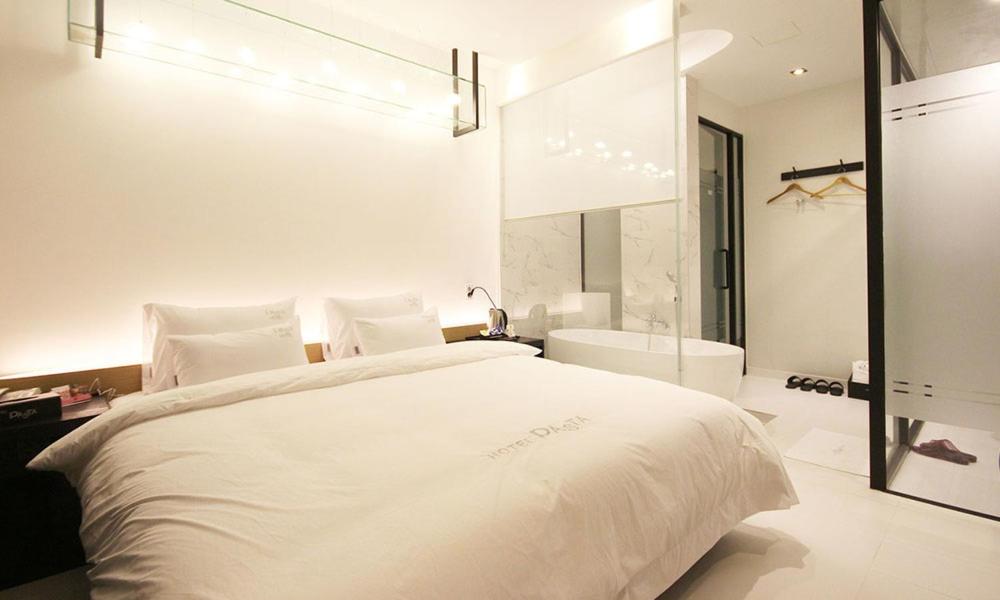 昌原市Jinhae Pasta Hotel的白色卧室设有一张大床和一个浴缸