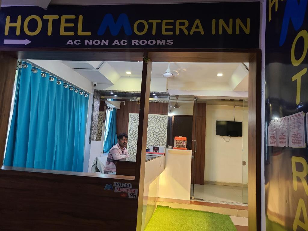 艾哈迈达巴德Hotel Motera Inn的坐在酒店办公室桌子上的男人