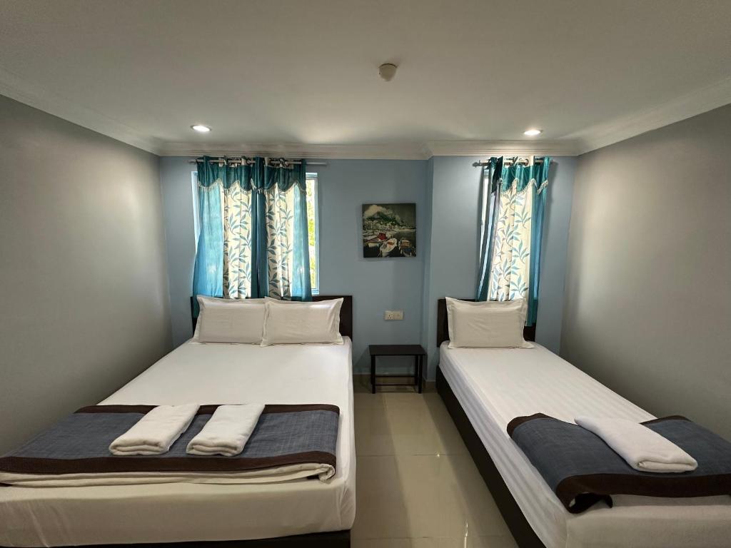 普崇玛哈酒店的配有两张床铺的蓝色墙壁和窗户
