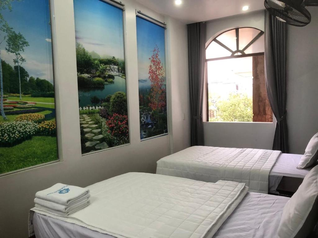 海防Hotel Nam Sơn Tân Dương的墙上画作的房间里设有两张床