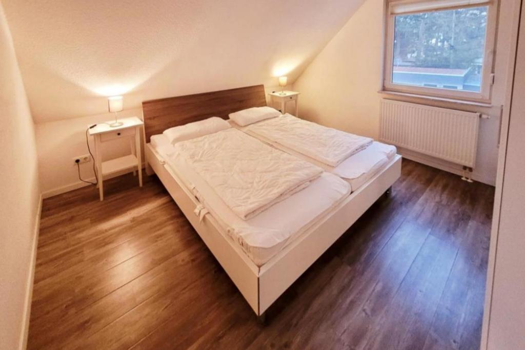 马林费尔德K 96 OG - charmante Ferienwohnung mit Badewanne und Sauna in Roebel Mueritz的一间卧室配有一张床、一张桌子和一个窗户。