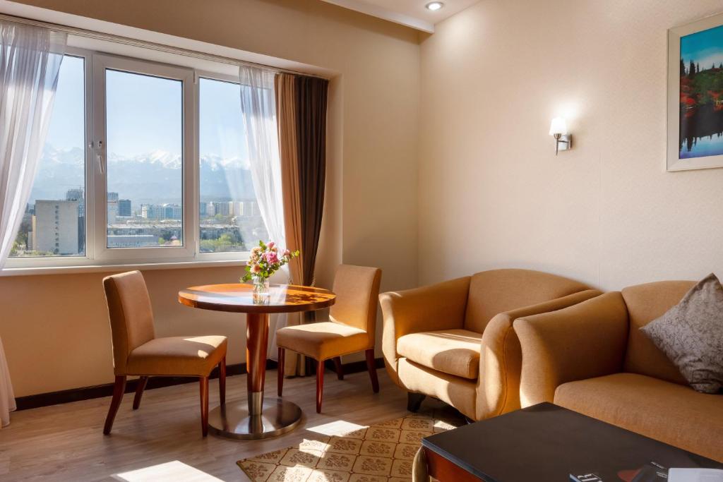 阿拉木图Regardal Hotel的客厅配有桌椅和窗户。