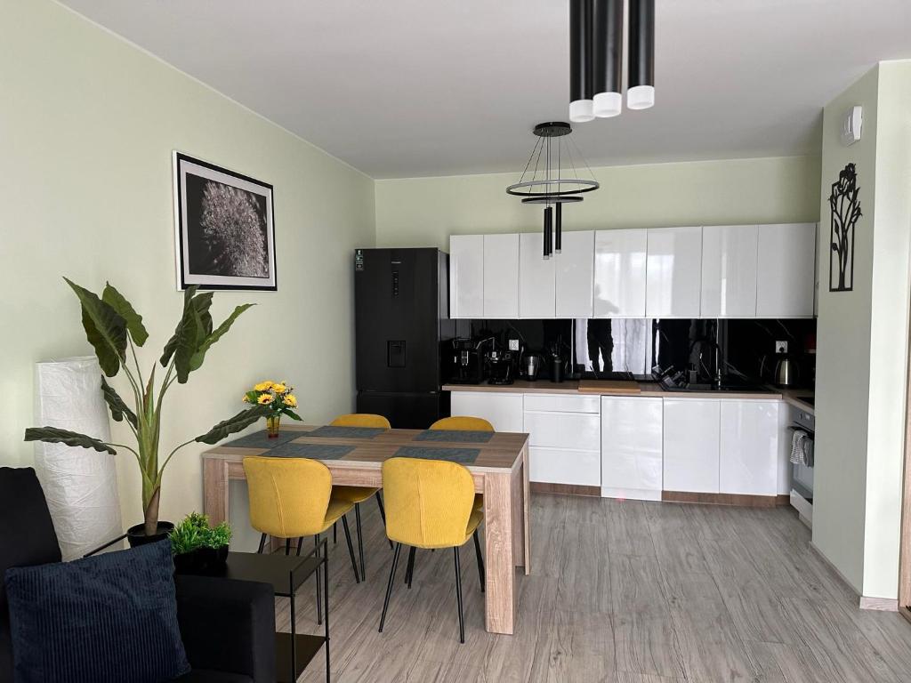 伊拉华Apartament NATURA z widokiem na jezioro的厨房以及带桌子和黄色椅子的用餐室。