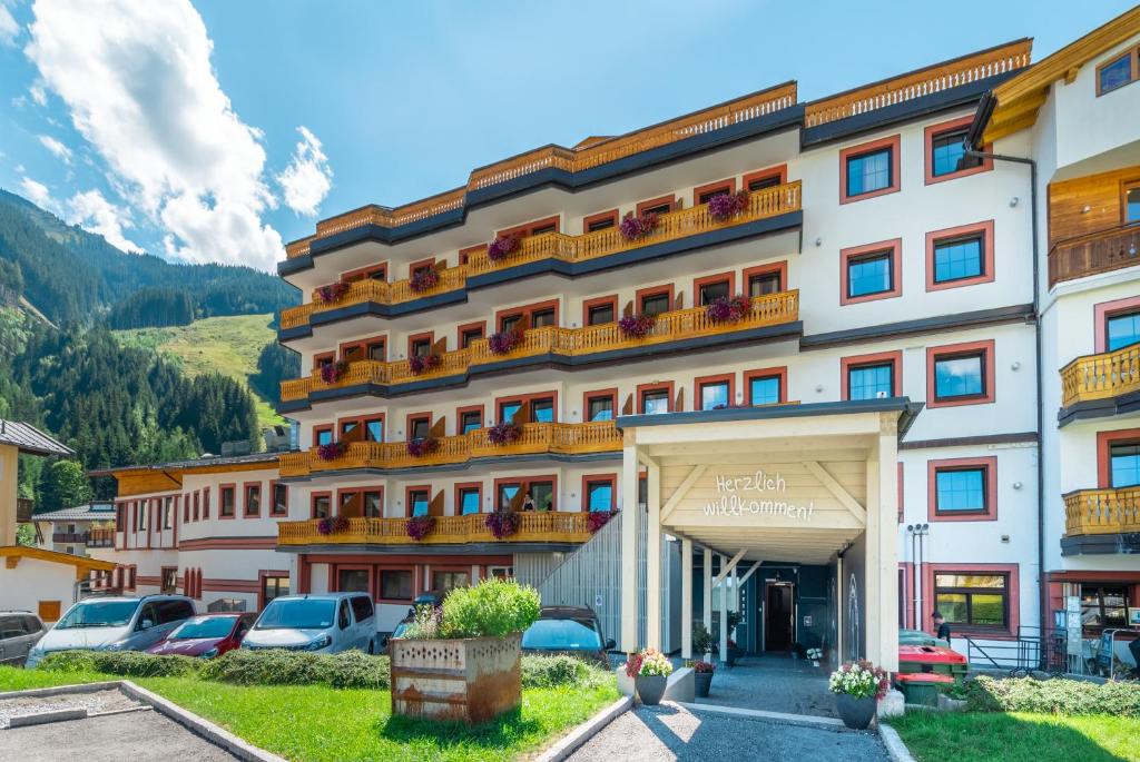 萨尔巴赫JUFA Alpenhotel Saalbach的停车场内有车辆的旅馆