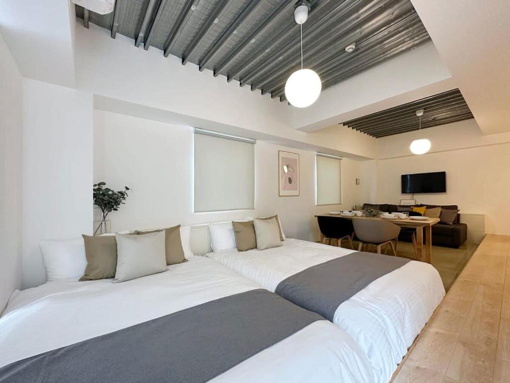 广岛bHOTEL Arts Dobashi - Cozy & Modern Studio Apt 5 Mins Walk to Peace Park的一张大白色的床,位于带桌子的房间