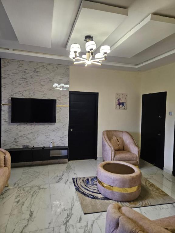 伊巴丹MDCUBE HOMES AND PROPERTIES的客厅配有2把椅子和平面电视