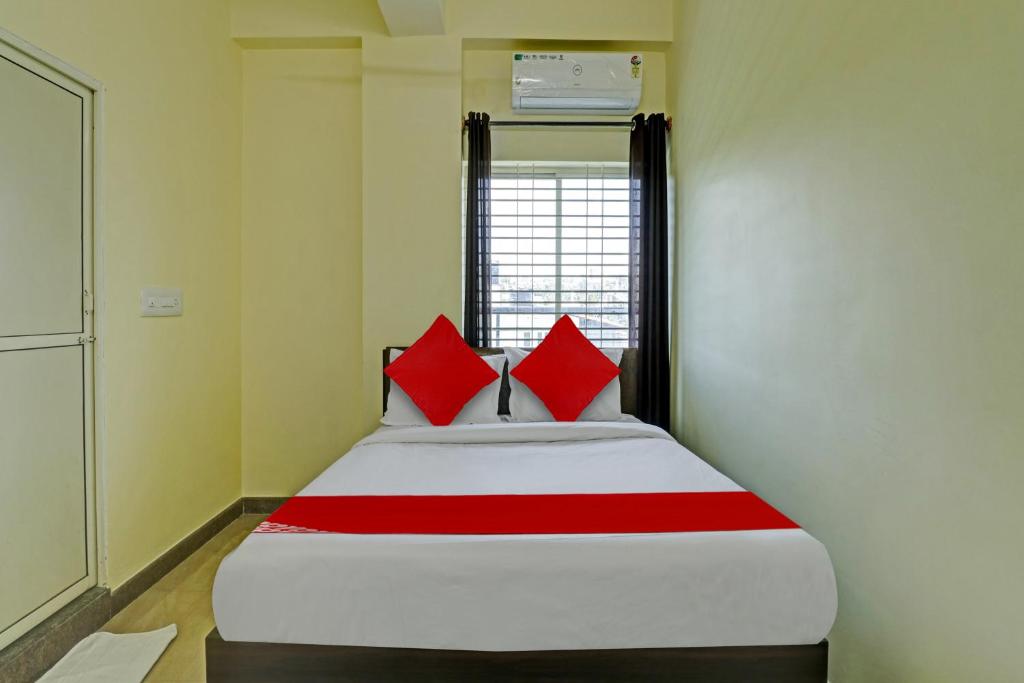 班加罗尔OYO Flagship Sri Chamundeshwari Boarding And Lodge的宿舍间内的一张床位,上面有红色枕头
