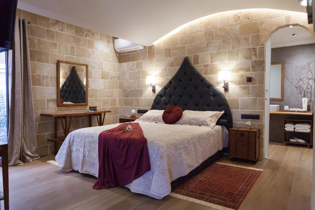 罗德镇Utopia Luxury Suites - Old Town的一间卧室设有一张大床和石墙
