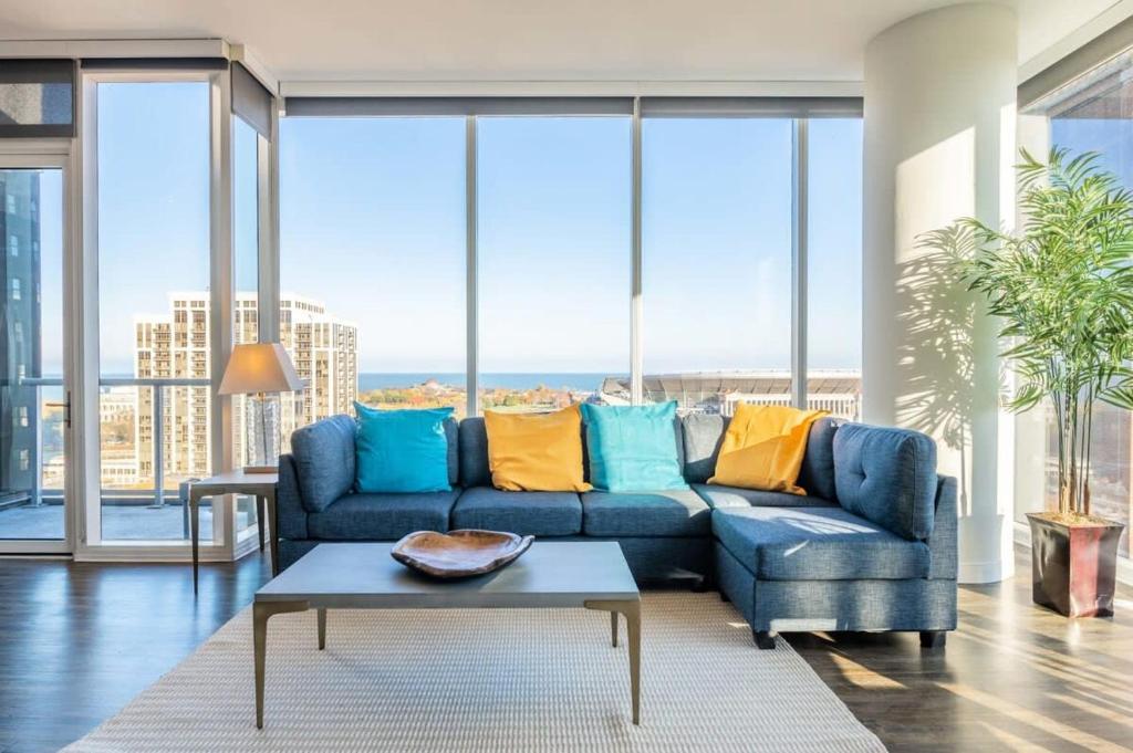 芝加哥3BR Luxury Glass Apartment With Views Pool & Gym的客厅设有蓝色的沙发和大窗户