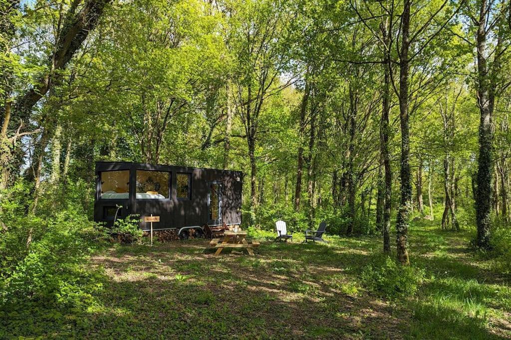 SonchampTiny House La Clairière au milieu des bois !的森林中的黑色帐篷,配有野餐桌