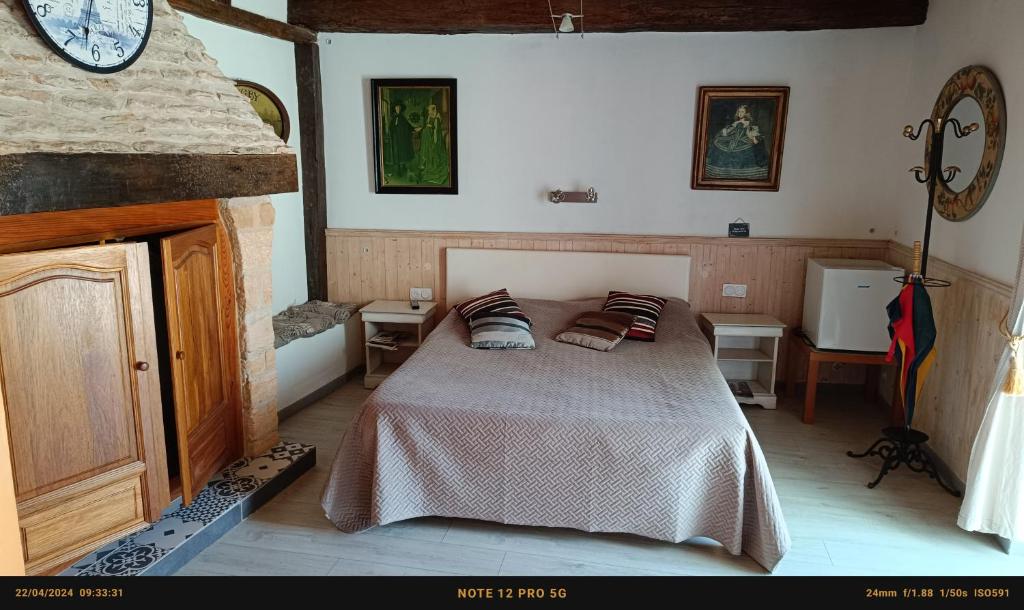 莱塞齐耶德泰阿克普热住宿加早餐度假屋的卧室配有一张床,墙上挂着一个钟