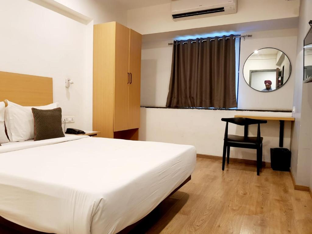 孟买Hotel Samrat, Mumbai的一间卧室配有一张床、一张书桌和一面镜子
