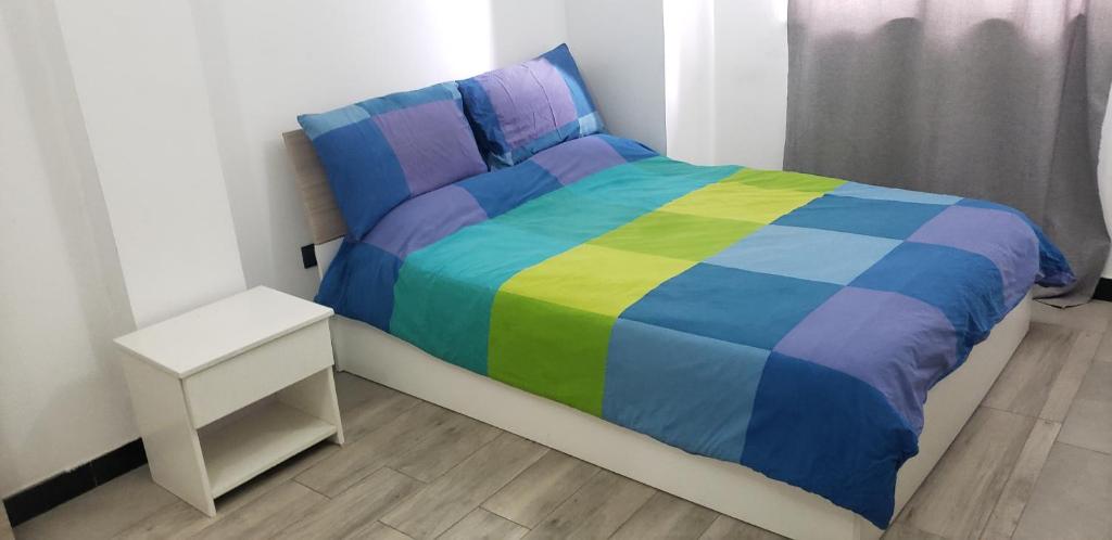 亚的斯亚贝巴LEYO FURNISHED APARTMENTS的一张带五颜六色的被子和边桌的床