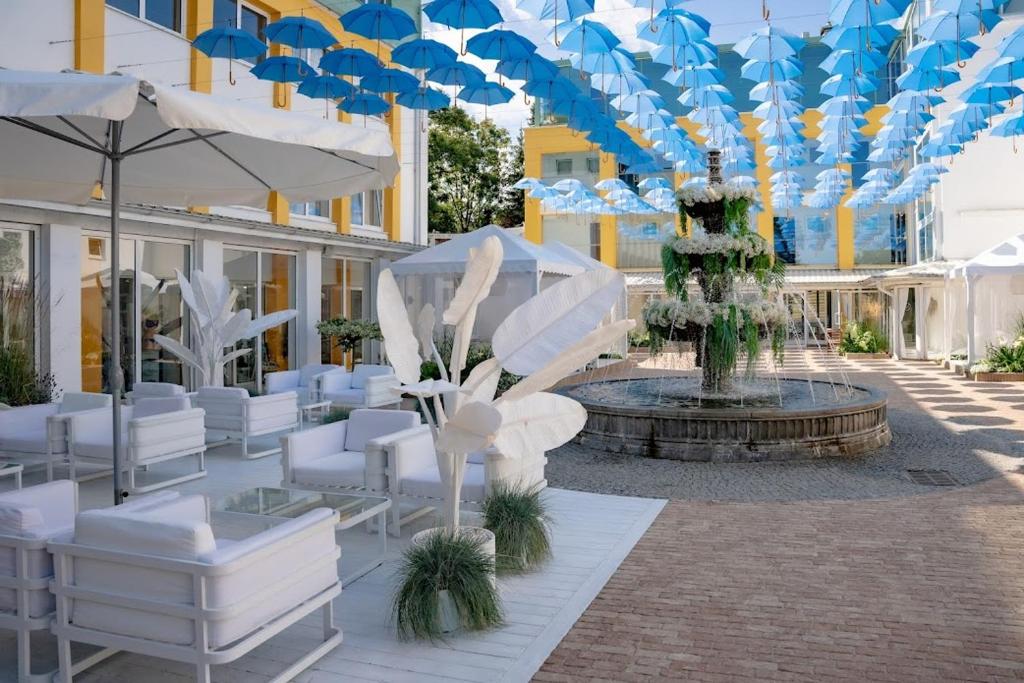 拉塔布来扎温泉度假酒店的庭院配有白色椅子和带遮阳伞的喷泉。