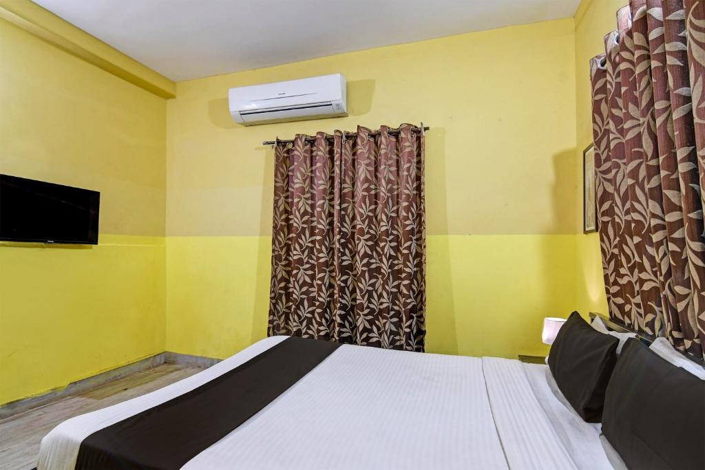 KhandagiriOYO Home Spacious Stay的一间卧室设有一张床、一台电视和一个窗口。