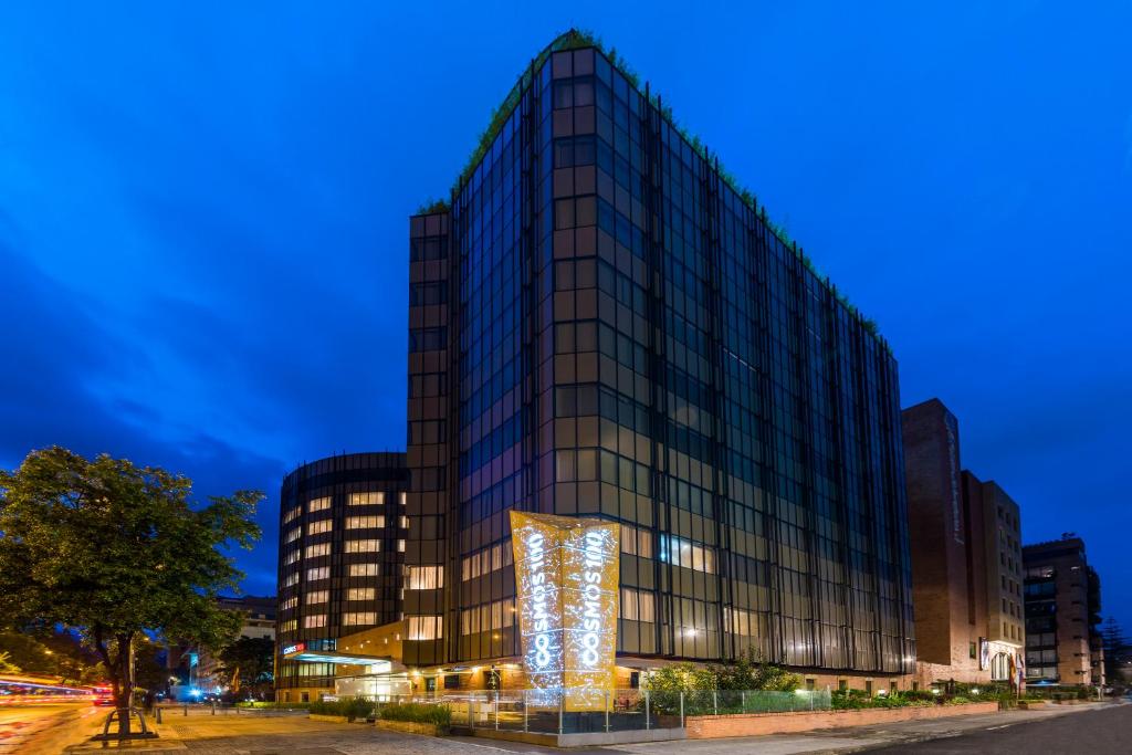 波哥大科斯莫斯100号酒店及会议中心的一座高大的玻璃建筑,外墙有灯光