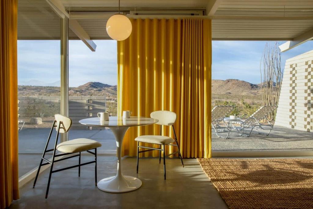 约书亚树The Bungalows by Homestead Modern的一间带桌椅和大窗户的用餐室