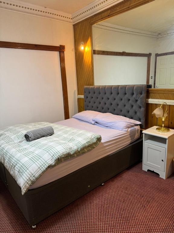 奥尔德姆Crete Room的一间卧室配有一张带床头板和桌子的床