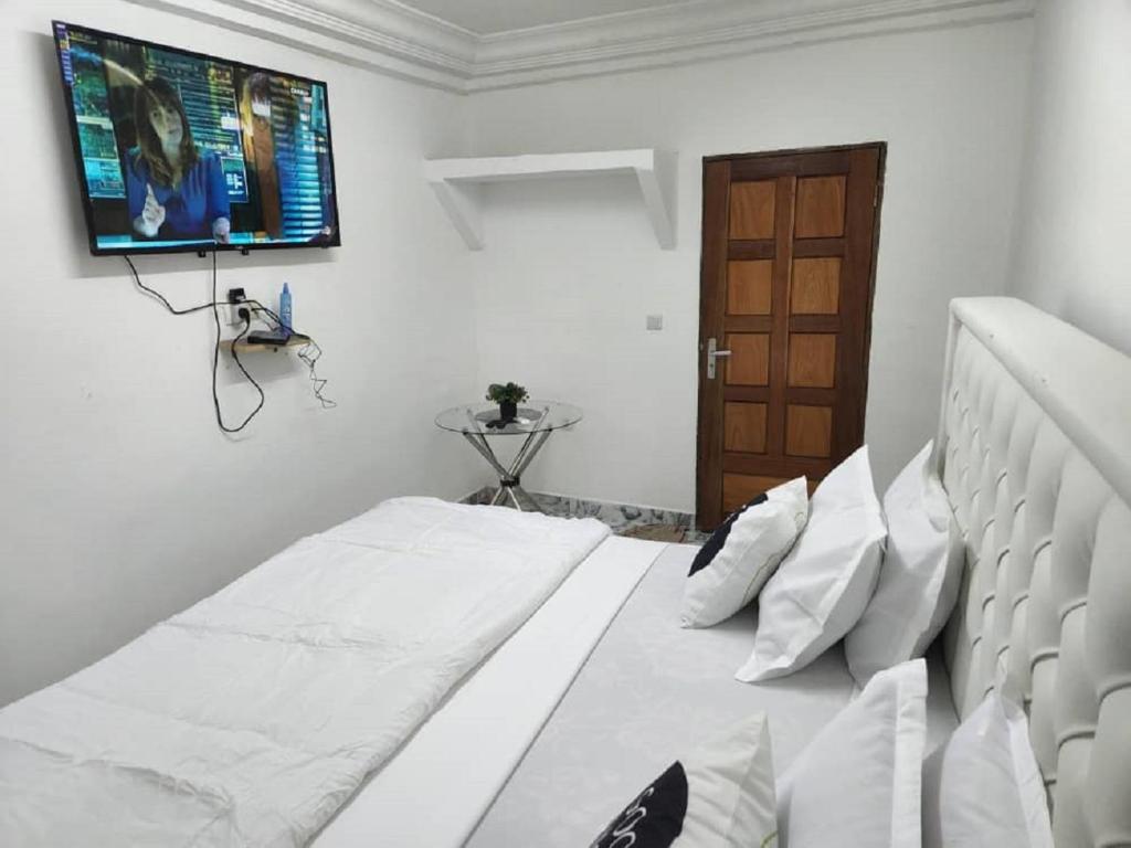 杜阿拉Chambre Meublée à Douala, Bonapriso - Armée del'air的卧室配有一张壁挂式平面电视的床。