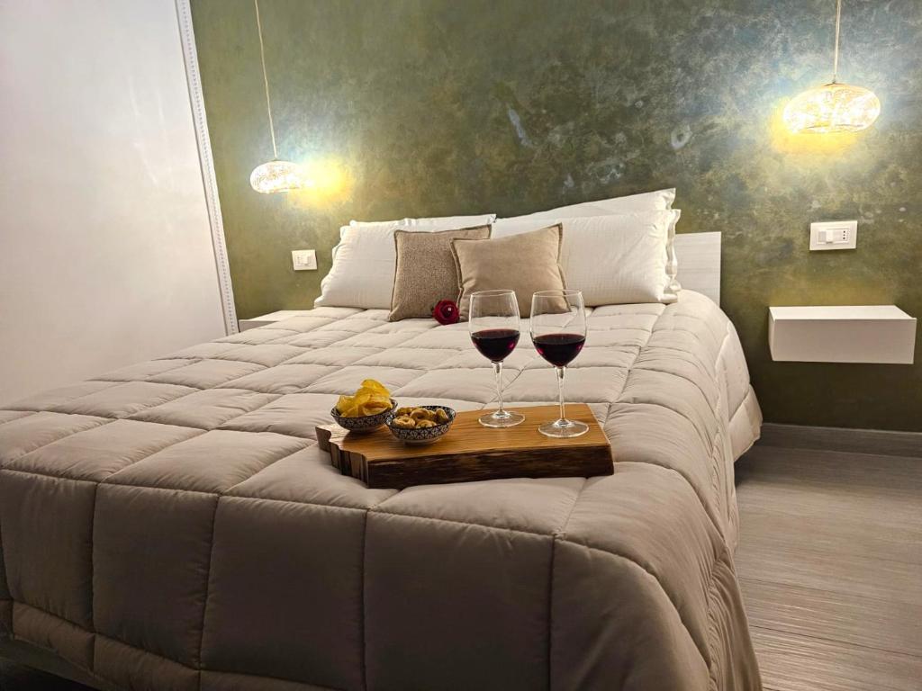 帕杜拉Casa Semeria Certosa di Padula(SA)的一间卧室配有一张带两杯葡萄酒的床