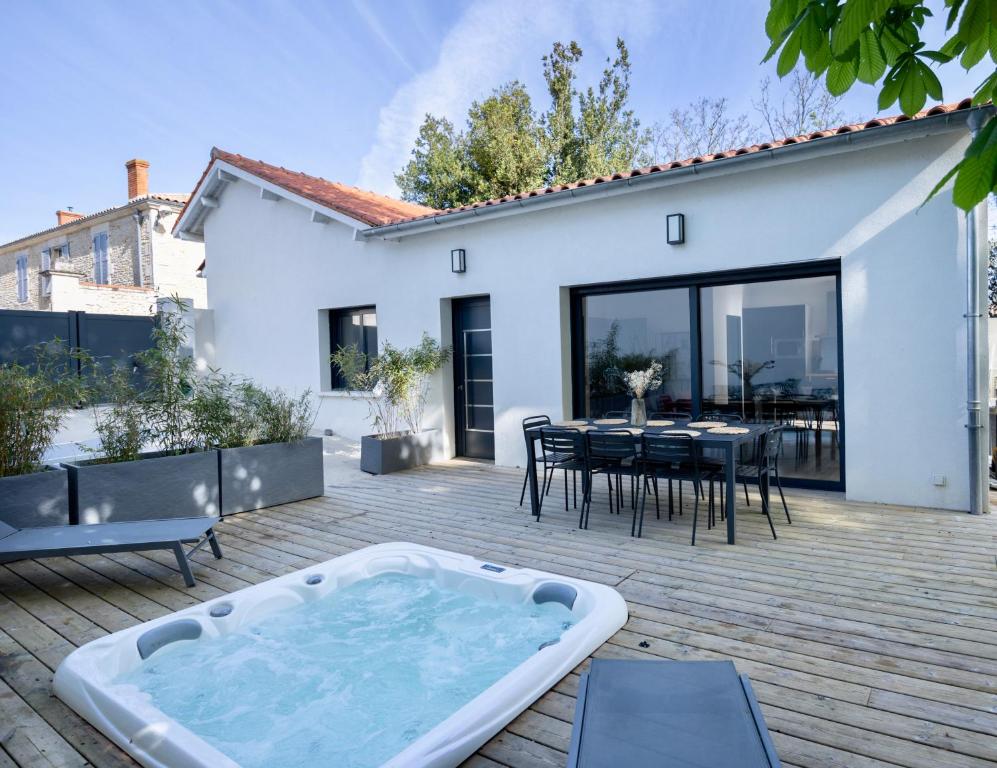 拉戈尔Maison T4 Climatisée avec Jacuzzi à Lagord的庭院内的热水浴池,配有桌椅