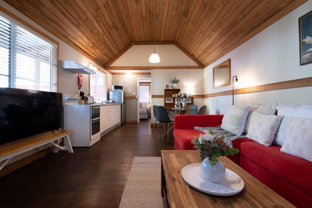 Kings ParkStation Cottage的客厅配有红色的沙发和桌子